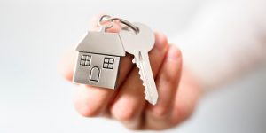 Holding house keys on house shaped keychain concept for buying a new home